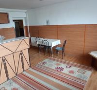 The interior of a building with a wooden decor floor, table, chairs, and a carpet.