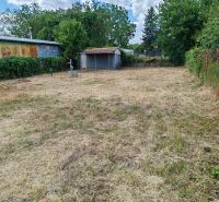 Gardens in Komárno with a lawn, trees, an older gazebo, and fencing.