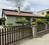 A family house in Chrabrany with a landscaped garden, fence, and driveway.