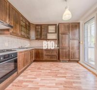 A kitchen in a 2-room apartment with a wooden decor and balcony doors.