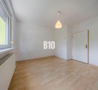 A room in a 2-room apartment with white walls and a wooden decor floor.