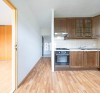 A kitchen with wooden cabinets and a floor with a wooden decor in a 2-room apartment.