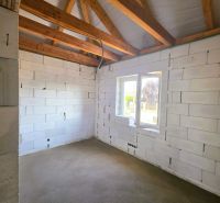 Interior of a family house with white block walls and unfinished wooden ceiling beams.