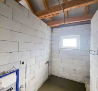Room in a family house with brick walls and an exposed wooden ceiling.