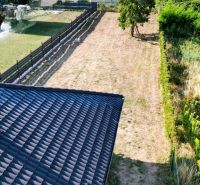 The roof of a family house in Čaňa with a yard surrounded by greenery and trees.