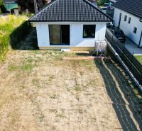 A family house in Čaňa with a simple garden and a black roof.