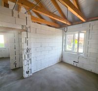 Interior of a family house with a wooden ceiling structure and concrete floor.