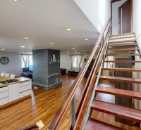 Interior of a family house with an open kitchen, wood-patterned flooring, and a staircase.