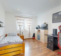 A room in a family house with a bed, a desk, and a floor with a wooden decor.