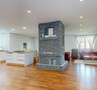 Living room with kitchen and fireplace, wooden decor flooring in a family house.