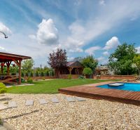 A garden of a family house in Lehota with a gazebo, a swimming pool, and a manicured lawn.