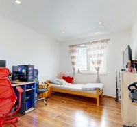 A room in a family house with a computer, a bed, and a wooden decor floor.