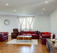 Living room in a family house with a fireplace, sofa set, and wooden decor flooring.