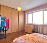 Bedroom in a family house with wood-patterned flooring, pink walls, and a wardrobe.