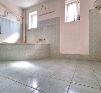 A bathroom in a family house with a tiled bathtub, toilet, and sink.