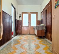 A hallway in a family house with colorful tiles and wooden wall paneling.