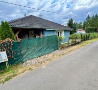 A family house in Ružiná with a blue facade, fencing, and surrounding greenery.