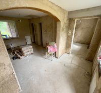 Interior of a family house with raw walls, construction materials, and a cardboard floor.