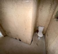 A toilet in an unfinished bathroom of a family house with damaged walls.