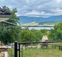 View from a family house in Ružiná of the lake, trees, and hills.