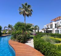 Residential complex with a pool and palm trees in Agia Eirini, surrounded by lush greenery.