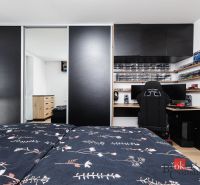 Bedroom in a 2-room apartment with a wardrobe, desk, and floor with wood decor.