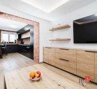 A kitchen in a 2-room apartment with brick details and a wooden decor floor.