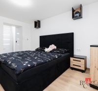 A bedroom in a two-room apartment with a black bed and a wooden decor floor.
