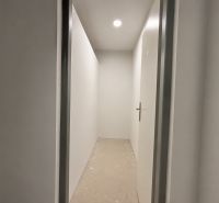 A narrow hallway with white walls and closed doors in a one-room apartment.