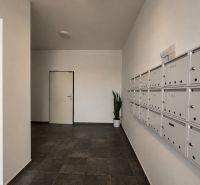 Entrance hall with mailboxes and gray tiles in a studio apartment.