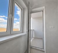 A spacious balcony with a view in a 1-room apartment, white walls and a blue sky.