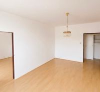 A room in a three-room apartment with a wooden decor floor and a chandelier.