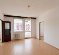 A spacious room with a wooden decor floor and two windows in a 3-room apartment.