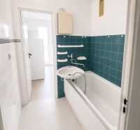 A bathroom with green tiles and a bathtub in a 3-room apartment.