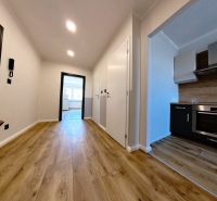 A hallway in a 3-room apartment with a wooden decor floor and an entrance to the kitchen.