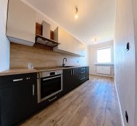 A bright kitchen with wood-patterned flooring in a three-room apartment.