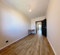 A room with a wooden decor floor in a 3-room apartment with a table and a light bulb.