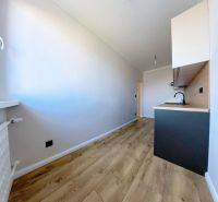 A kitchen in a 3-room apartment with a wooden decor floor and light walls.