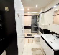 The bathroom of a 3-room apartment with a modern shower, white furniture, and tiles.