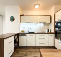 A kitchen with white cabinets, a wooden decor floor, in a 3-room apartment.