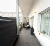 Balcony of a 3-room apartment with a wooden decor floor and outdoor seating.