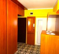 A hallway in a 4-room apartment with wooden furniture and patterned flooring.