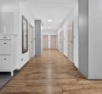 A hallway in a family house with a wooden decor floor and white furniture.