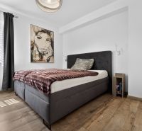 Bedroom in a family house with a bed, painting, and floor with wood decor.