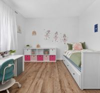 Children's room in a family house with a wooden decor floor, a bed, and a desk.