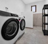 Laundry room in a family house with a washing machine, dryer, and storage shelves.