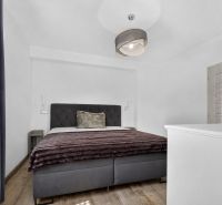 Bedroom in a family house with a gray bed, blanket, and floor with a wood decor.