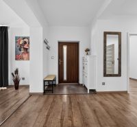 Entrance hall of a family house with a wooden decor floor, a painting, and a mirror.