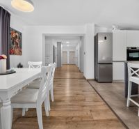 A dining room in a family house with white furniture and a wooden decor floor.