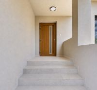 Entrance stairs and door in a family house with light-colored walls and railing.